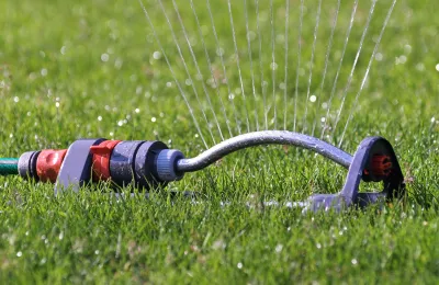Lawn sprinkler on grass, connected to an automated irrigation control line